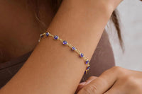 The evil eye bracelet worn on a wrist, showcasing the adjustable 7 inch 14K gold plated chain with protective blue evil eye charms.