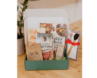 Book Box for a book lover who also enjoys spending time in the kitchen. The box has two novels, a cookbook, chocolate, and kitchen items.