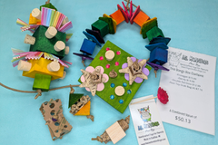 A variety of bird toys spilling out of a cardboard box and onto a blue cloth. Next to it is an itemized receipt and a business card. 