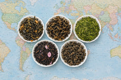 Five rare loose-leaf teas from The Tea Smith's Expedition range in white dishes on a world map, from Colombia, Nepal and Japan
