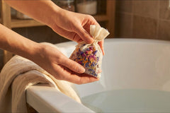 Woman hands holding ILUVNIKI luxury bath ritual sachet filled with lavender rose botanicals for nervous system support