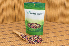 An open Tea Smith club pouch of Blue Butterfly Garden herbal tea, lemongrass with butterfly pea flowers and rose, with a scoop of it