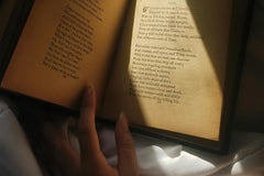 A person holding an open hardcover book with red edges, showcasing a cozy reading moment for book lovers with the Fantasy Books Club subscription
