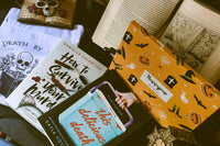 Death by TBR book sleeve, book How to Survive Your Murder, one book This Delicious Death, Halloween sock box, skull statue, open book