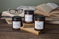 image shows three candles at staggering heights. one candle sits atop a book and one candle sits atop a stack of two books.