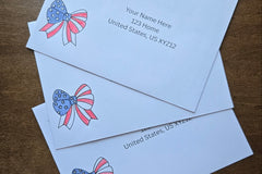 Three white envelopes with printed sample U.S. mailing addresses and red, white and blue patriotic bow designs featuring stars and stripes.