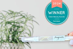 Hand holding the Clean Beauty Award- Winning Honeysuckle Botanical Cuticle Oil Pen by Greenmade goods with the Clean Beauty Award Seal.