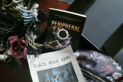 This is a picture of the book title Peripheral, the Black Rose newsletter, skull plant decor, and skull purse inside the box.