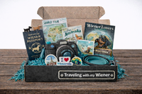 Example Cult of Wiener subscription box displayed open, showing themed dachshund items, magazine, toys, and curated accessories.