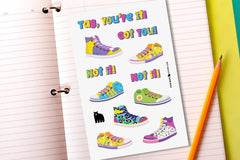 An open ring binder with lined paper, a pencil and a sticker sheet featuring the words "Tag, You're It" and brightly coloured sneakers.