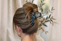 a black and white polka dot large claw clip shown in a casual twisted full up hairstyle on brown hair