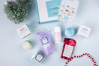 A person holds a teal Bath Bevy monthly subscription box tied with a red ribbon, ideal for self care gifts