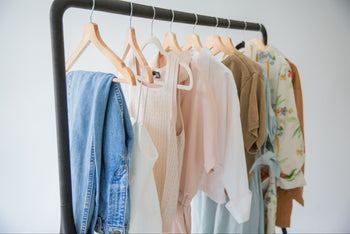 a rack of vintage garments for spring, floral print wraps, cotton blouses and denim jeans, all perfect layering pieces for the season