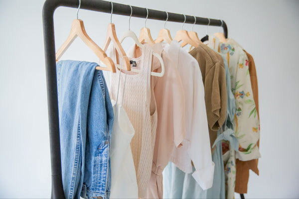 a rack of vintage garments for spring, floral print wraps, cotton blouses and denim jeans, all perfect layering pieces for the season