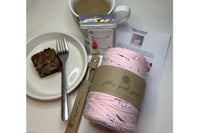 Pink T-shirt yarn with a bamboo hook.  Chocolate brownie made with the baking kit. Cup of tea and stitch marker.