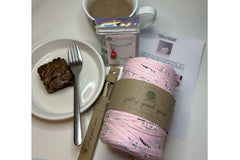 Pink T-shirt yarn with a bamboo hook.  Chocolate brownie made with the baking kit. Cup of tea and stitch marker.