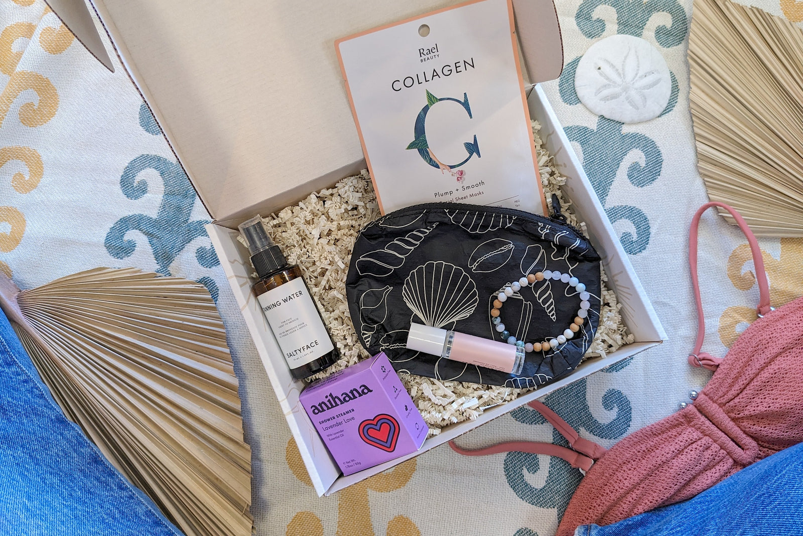 The open Palm People subscription box shows the following products: shower steamer, bracelet, small bag, tanner, perfume, and face mask.