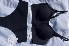 A flat lay picture of matching black seamless bra and thong from the brand okko on a white background 