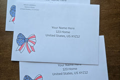Three white envelopes with printed sample U.S. mailing addresses and red, white and blue patriotic bow designs with stars and stripes.