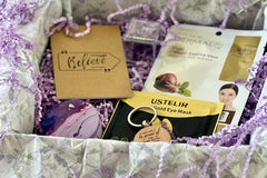 Opened Purple Box, where you can see keychain, eye mask, face mask, scented candle, notepad to clear your mind.