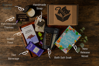 Introverts Retreat flatlay on wood with each item and the box. Items are labeled with white lettering.