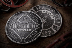 Very Hugh quality and close up photo of 2 tokes or coins with the word arcade and spaced out on them.