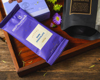 Introverts Retreat box items including a purple bag of dark chocolate cocoa on a tray with chocolate covered nuts.