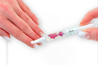 A Greenmade goods Rose Cuticle Oil held in the right hand, applying to the left against a light background.