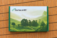 Image of the tea of the month box closed with tea field image across the box with the Tea Smith logo on a bamboo background.
