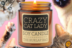 Crazy Cat Lady 9oz soy candle by The Burlap Bag, grapefruit scented amber jar surrounded by cat faces on a pink background