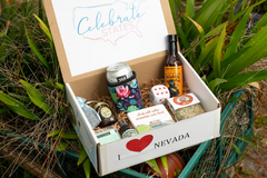The Nevada Box shows what customers received by showcasing an open box with a drink, dice, coaster and various food items.