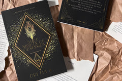 Black cover with gold foil designs. The title 5000 Nights of Obsession appearing on the cover. A gold peacock feather in the center. 