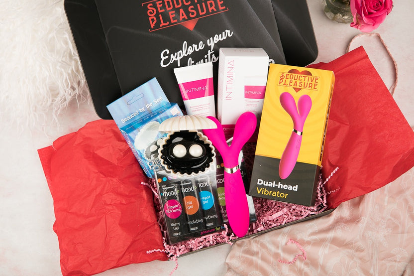 Colorful items including a pink dual-head vibrator and massage oils in the Woman SOLO Adult Subscription Box for self exploration
