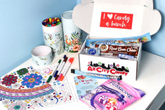 Boxes can be gifted for all occasions.  Shown here on table with art supplies.  Colorful box with sticker opened to show sweet candy treats.