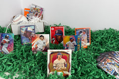 Baseball cards from a subscription box, arranged on a green grass base, with a box and baseball with the cards
