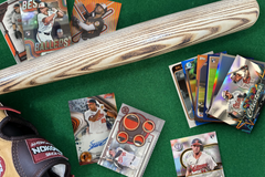 Baltimore Orioles baseball cards arranged in flat lay format on a green carpet with a baseball glove and bat