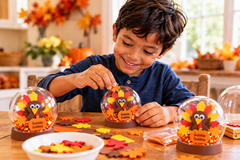 A child works on a Thanksgiving turkey glitter globe craft, with colorful decorations and fall-themed supplies nearby