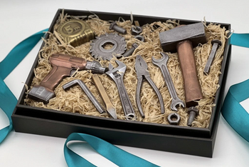 Gift box featuring a realistic chocolate drill, hammer, saw blade, pliers, tape measure, and assorted tool-shaped treats