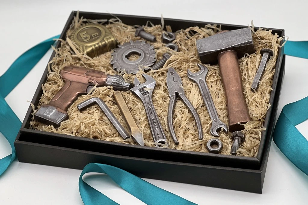 Gift box featuring a realistic chocolate drill, hammer, saw blade, pliers, tape measure, and assorted tool-shaped treats