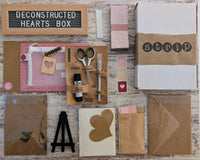 Contents of the Deconstructed Hearts Box including paper bundle, greeting cards, heart cutouts, envelope seals, foam pop dots, and an easel.