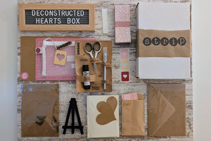 Contents of the Deconstructed Hearts Box including paper bundle, greeting cards, heart cutouts, envelope seals, foam pop dots, and an easel.
