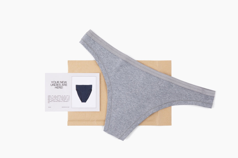 Pair of underwear (gray thong) featured in the monthly subscription along with a notecard and shipping mailer