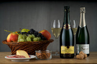 Items from Club Cuvée - Champagne Club subscription box including 2 bottles of champagne, a basket of fruit, and almonds.