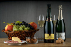 Items from Club Cuvée - Champagne Club subscription box including 2 bottles of champagne, a basket of fruit, and almonds.