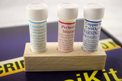 A blue box containing a forensikit is displayed in the back while a 3 chemicals for luminol science STEM experiments are in the foreground