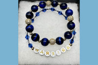 Handmade encouragement bracelet with deep blue stone beads, light blue faux crystal accents, and white letter beads spelling “WARRIOR” 