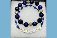 Handmade encouragement bracelet with deep blue stone beads, light blue faux crystal accents, and white letter beads spelling “WARRIOR” 