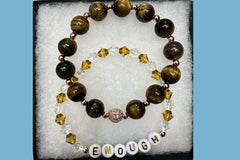 Handmade encouragement bracelet with earthy brown stone beads, amber faux crystal accents, and white letter beads spelling “ENOUGH” 