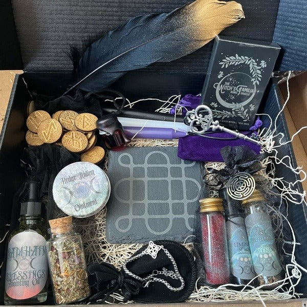 Busy Witch Samhain spread with a black feather, Samhain blessings oil, herb jars, coins and a witch's journal