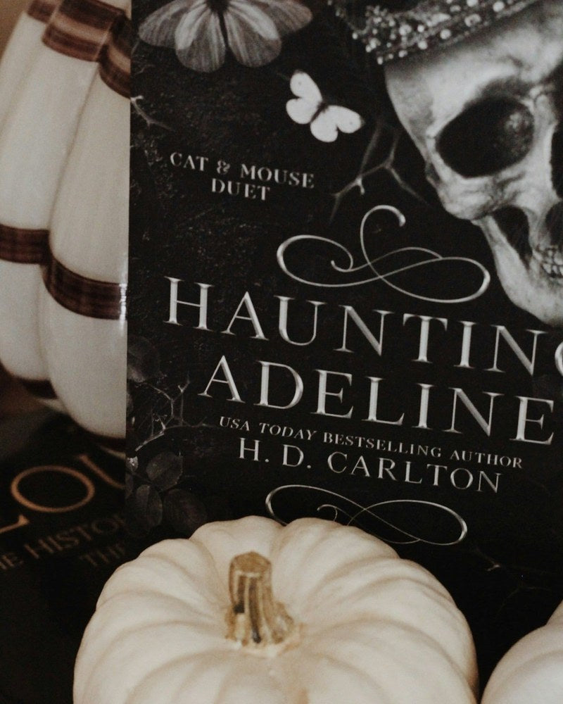 Haunting Adeline horror novel beside white pumpkins